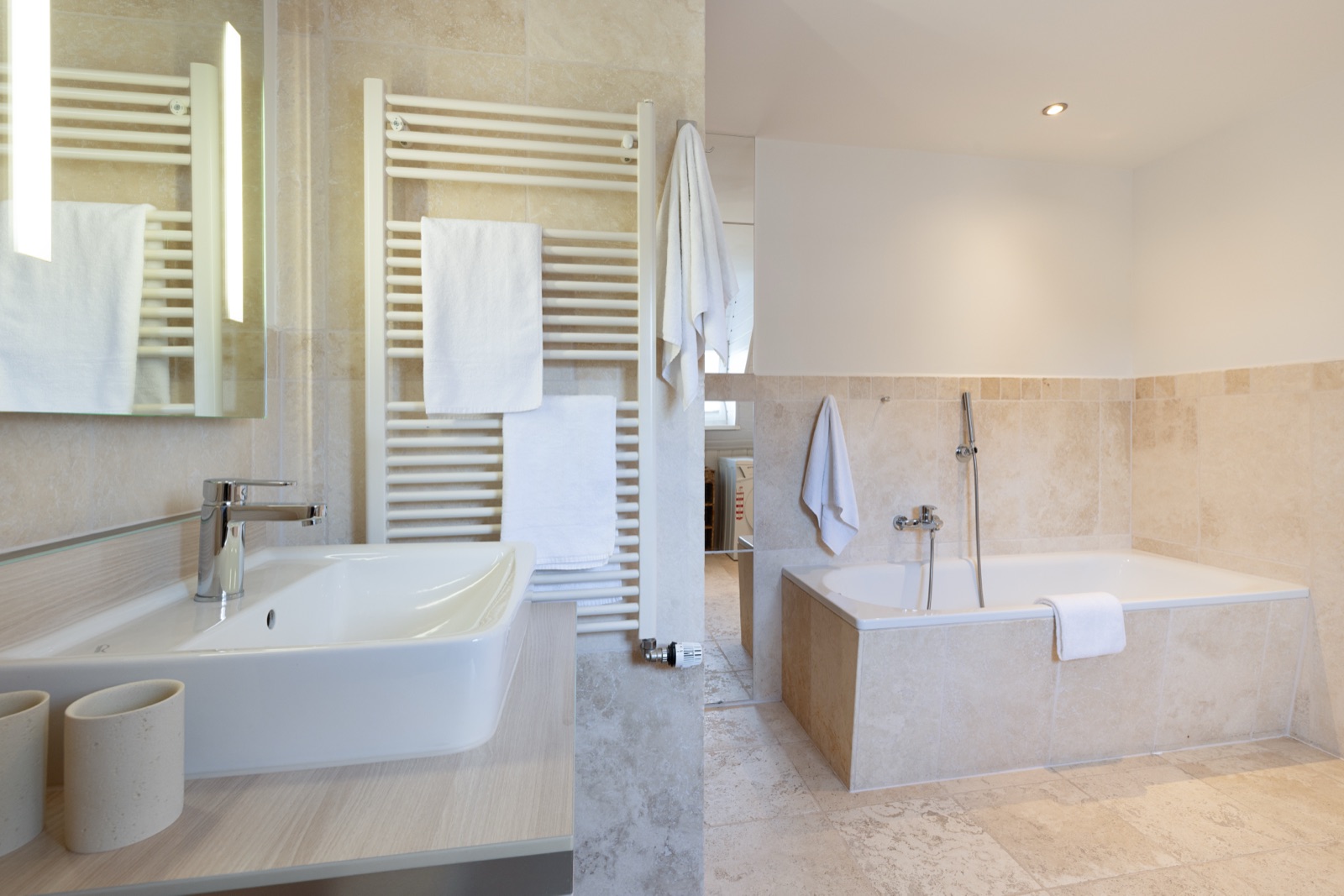 Travertin-Badezimmer mit Eckbadewanne unter der Dachschräge