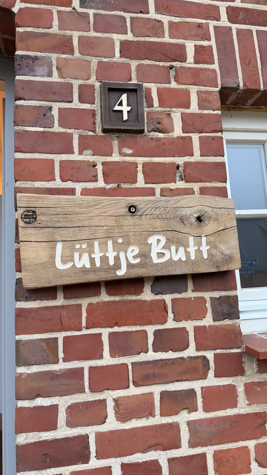 Holzschild „Lüttje Butt“ und Hausnummer 4 an der Backsteinfassade