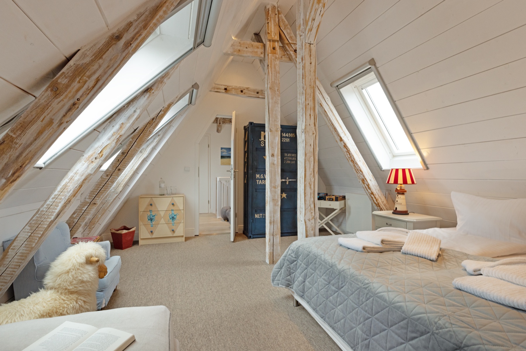 Schlafzimmer unterm Dach mit alten Holzbalken und Leuchtturm-Lampen